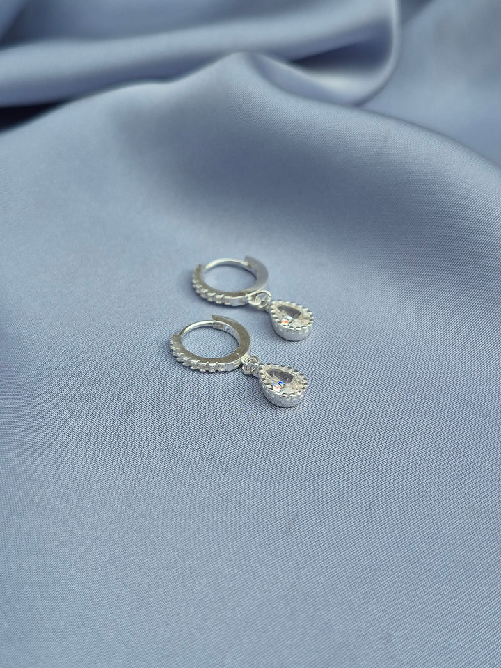 اقراط دائرية من الفضة مرصعة بحبات الزركون وبتدلى منها قطرة مرصعة بالزركون